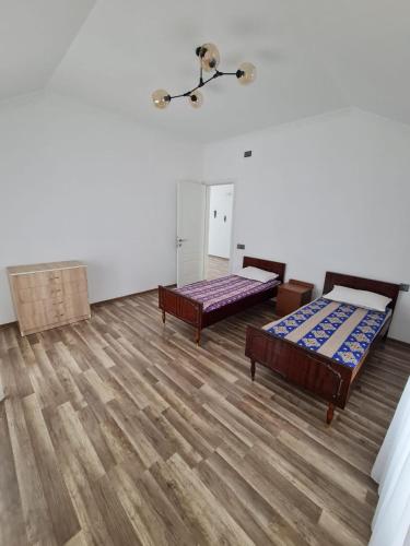 a large room with two beds and wooden floors at Gulu Cottage House in Mərdəkan