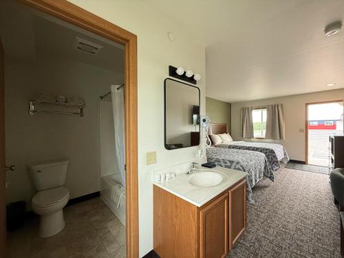 a bathroom with a sink and a toilet and a bed at The Trail Inn & RV Sites - Selby, SD - HWY 12, HWY 83 in Selby
