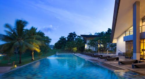 a swimming pool with lounge chairs next to a building at Novotel Manado Golf Resort & Convention Center in Manado