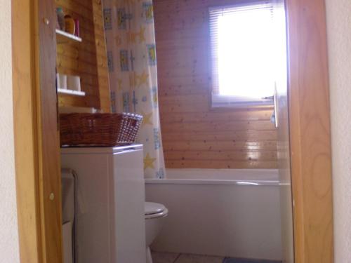 La salle de bains est pourvue de toilettes, d'une baignoire et d'une fenêtre. dans l'établissement Maison bois dans village vacances 8 personnes, à La Teste-de-Buch