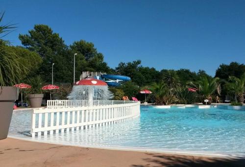 un parc aquatique avec une fontaine au milieu d'une piscine dans l'établissement Maison bois dans village vacances 8 personnes, à La Teste-de-Buch
