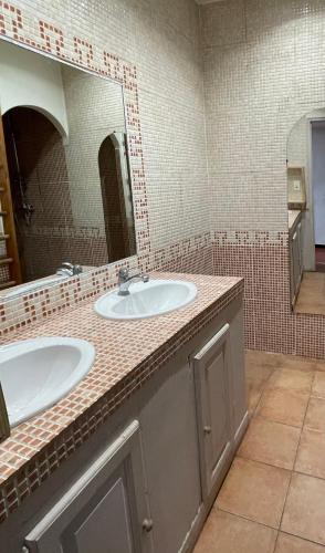 une salle de bain avec deux lavabos et un grand miroir dans l'établissement Maison de vacances en pleine nature, à Aurons