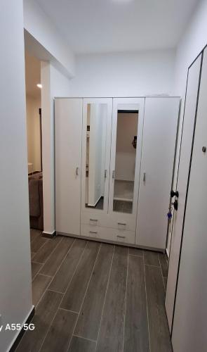 a room with white cabinets with mirrors and a wooden floor at Zen Studio Apartman in Kotor