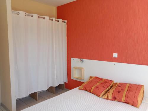 une chambre avec un lit et un mur rouge dans l'établissement Appartement neuf dans maison individuelle, à Bergerac