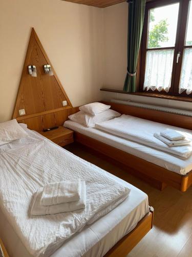 two beds in a room with two windows at Hotel Bayerischer Hof Rehlings in Weißensberg
