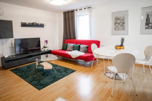 a living room with a red couch and a table at Flat at border suisse in Saint-Louis