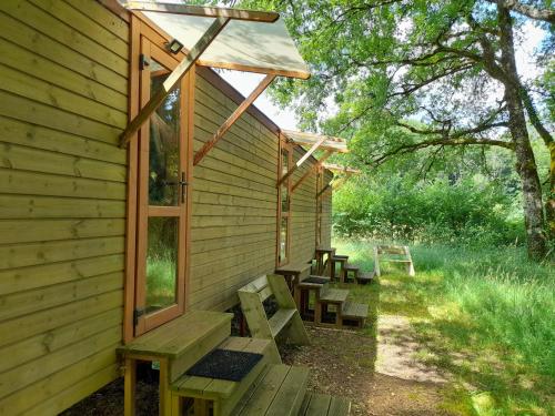 un bâtiment en bois avec des bancs sur le côté dans l'établissement Chambres en roulotte sur lieu atypique de ressourcement, à Mauzac-et-Grand-Castang