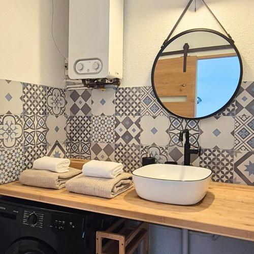 une salle de bain avec un lavabo et un miroir sur un comptoir dans l'établissement T2 Cozy a 2 min à pied des plages - Parking privé, à Palavas-les-Flots