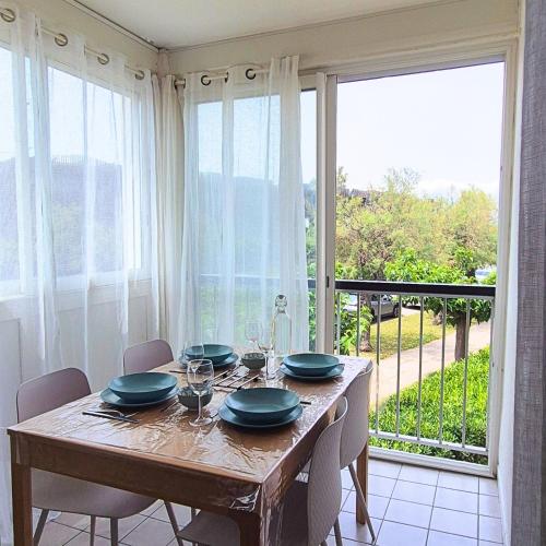 une salle à manger avec une table et une grande fenêtre dans l'établissement T2 Cozy a 2 min à pied des plages - Parking privé, à Palavas-les-Flots