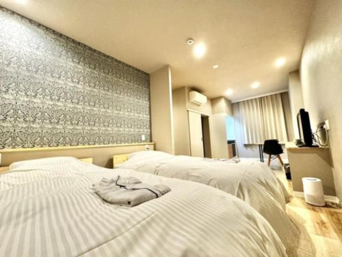 Beppu Onsen Resort Stay SPA TSURUMI - Vacation STAY 48229v في بيبو: غرفة فندقية بها سريرين مع مناشف عليهما