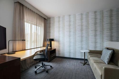 a hotel room with a desk and a couch and a desk and chair at Residence Inn by Marriott Houston NW Cypress in Cypress