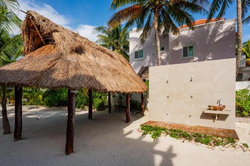 a building with a straw umbrella on the beach at Arenika Beach House in Puerto Morelos