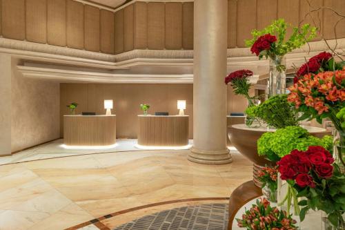 a lobby with a row of tables with red flowers at Sheraton Jumeirah Beach Resort in Dubai
