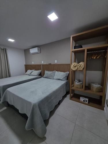 a bedroom with two beds and a book shelf at Apartamento em Arraial do Cabo in Arraial do Cabo