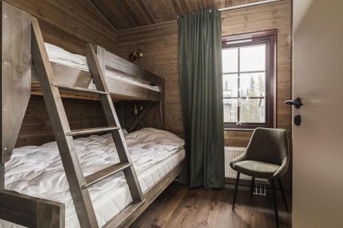 a bedroom with bunk beds with a chair and a window at Parkstigens Fjällby - Kåvan in Funäsdalen