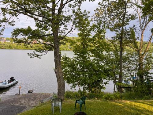 a boat on a lake with a tree and chairs at Camping Chalets Lac St-Augustin in Quebec City