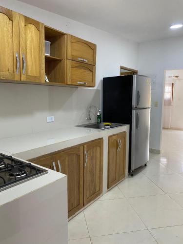 a kitchen with wooden cabinets and a stainless steel refrigerator at Blanca House in Arboletes