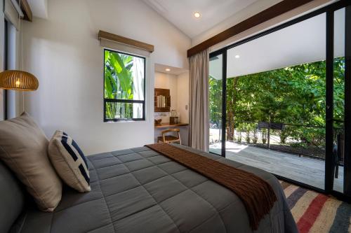 a bedroom with a large bed and a large window at Synergy Costa Rica in Uvita