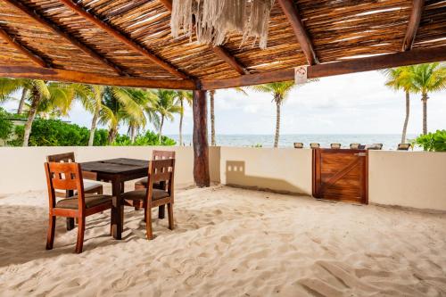 a table and chairs in the sand on the beach at Arenika Beach House in Puerto Morelos