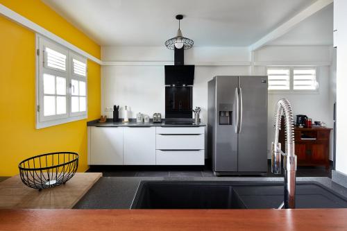 a kitchen with a stainless steel refrigerator and yellow walls at Villa Anj'any DESHAIES - 5 minutes à pieds de la plage in Deshaies