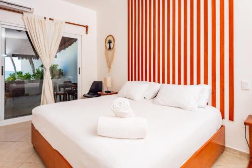 a bedroom with a large white bed and a window at Arenika Beach House in Puerto Morelos
