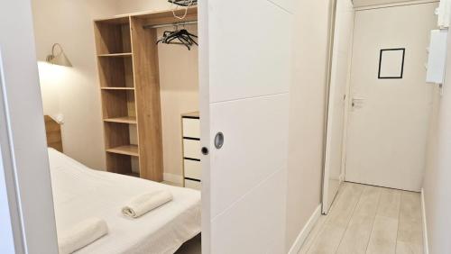 Cette petite chambre blanche comprend un lit et un miroir. dans l'établissement Appartement cosy, climatisation, proche mer, à Nice