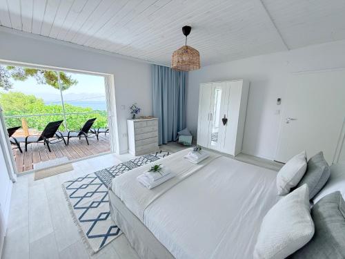 a white bedroom with a large bed and a balcony at Amara Blue Bay Villa in Kalamos