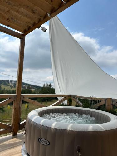 a hot tub on a deck with a white umbrella at Azalea Chalet in Divčibare
