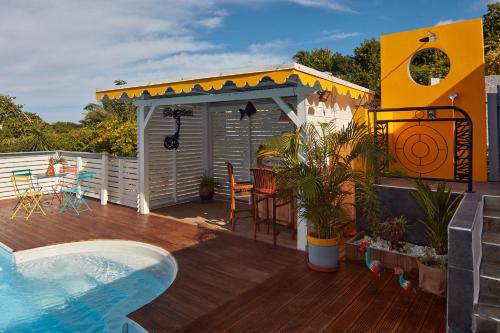 a deck with a swimming pool and a house at Villa Anj'any DESHAIES - 5 minutes à pieds de la plage in Deshaies