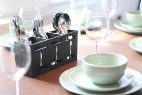 a wooden table with plates and forks and wine glasses at Spacious Home - 4 Bedrooms - Sleeps 9 - FREE Superfast 1GB Wi-Fi - 55" Smart TV - FREE Parking in Newcastle upon Tyne