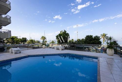 a large swimming pool with chairs and a blue sky at Barra Palace Hotel in Rio de Janeiro