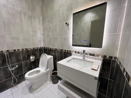 a bathroom with a toilet and a sink and a mirror at سويت بغرفة نوم وصالة جانبية in Hail