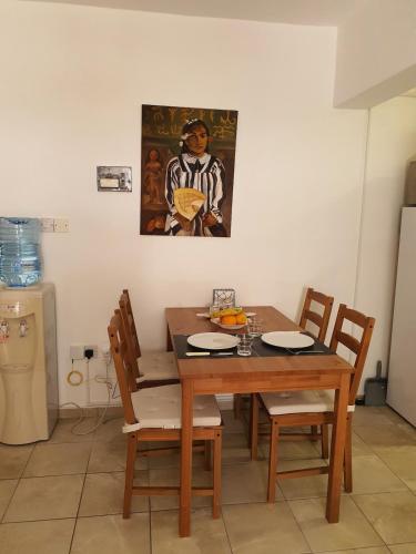 a dining room table with chairs and a painting on the wall at Lovely ground floor apartment with BBQ in Aglantzia