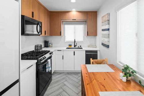a kitchen with white cabinets and a wooden table at Modern 1 BR Beach Waves and Sunshine in San Diego