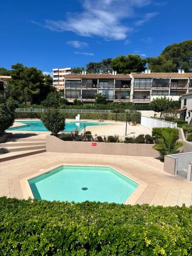 une grande piscine dans une cour avec un bâtiment dans l'établissement Tamaris les jardins alizarines, à La Seyne-sur-Mer