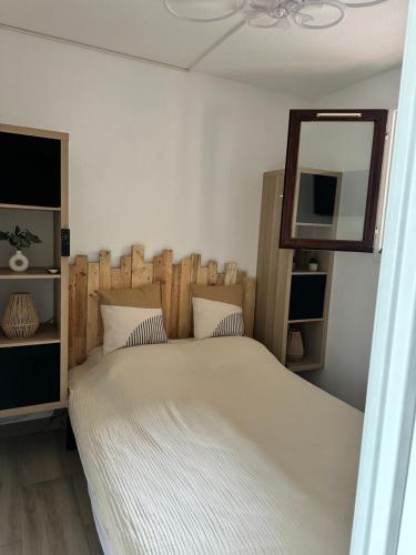 - une chambre avec un lit doté d'une tête de lit en bois et d'un miroir dans l'établissement Tamaris les jardins alizarines, à La Seyne-sur-Mer