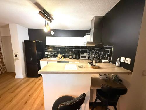 une cuisine avec des murs noirs et un comptoir avec des chaises dans l'établissement Cosy T3 - 70 m2 -Montpellier centre ville - Parking, à Montpellier