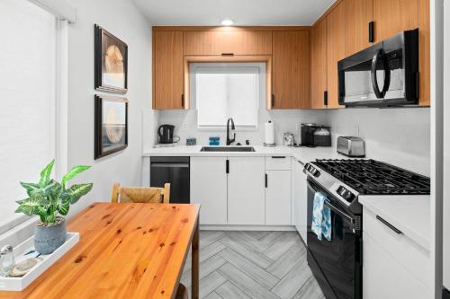 a kitchen with white cabinets and a wooden table at Modern 1 BR Apt - Walk to Ocean & Cafes in San Diego