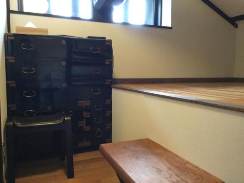 a room with two tall suitcases and a wooden table at Honmachi Juku in Hikone