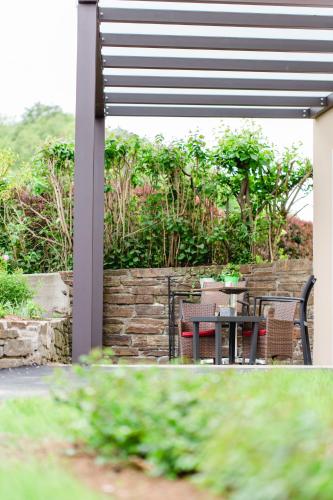 a patio with a table and chairs and a stone wall at Villa zur Schmied'n in Ehrenhausen