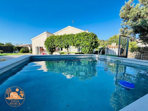 une piscine avec de l'eau bleue devant une maison dans l'établissement Villa Nuala, à Lignan-sur-Orb