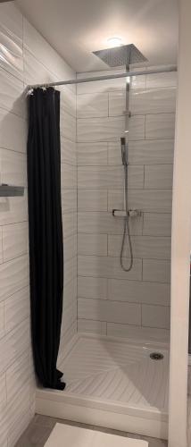 La salle de bains est pourvue d'une douche avec rideau de douche noir. dans l'établissement Le NINI HOME, à La Grande Motte