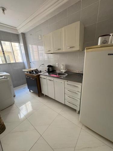 a kitchen with white cabinets and a refrigerator at Viva Alta Residence in Gurupi