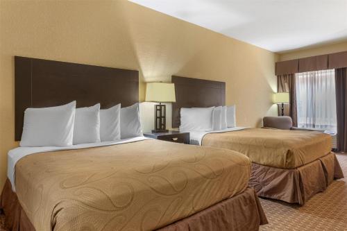 a hotel room with two beds and a chair at Best Western Bastrop Pines Inn in Bastrop