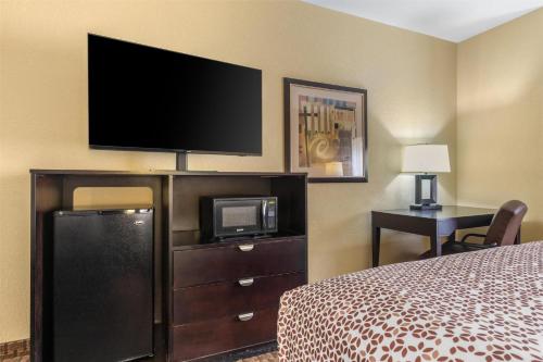a bedroom with a bed and a tv and a dresser at Best Western Bastrop Pines Inn in Bastrop