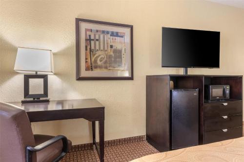 a hotel room with a desk and a flat screen tv at Best Western Bastrop Pines Inn in Bastrop