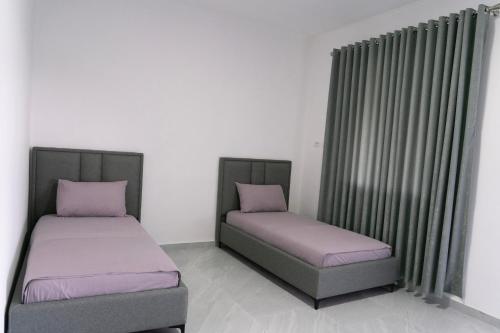 two twin beds in a room with curtains at KAFUL APARTMENTS in Qeparo