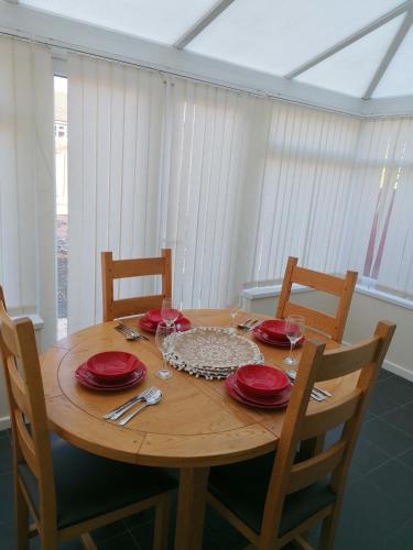 a wooden table with red plates and wine glasses at 3 BR l Family & Contractors l Parks 3 cars ,near Zoo , NEC in Dudley