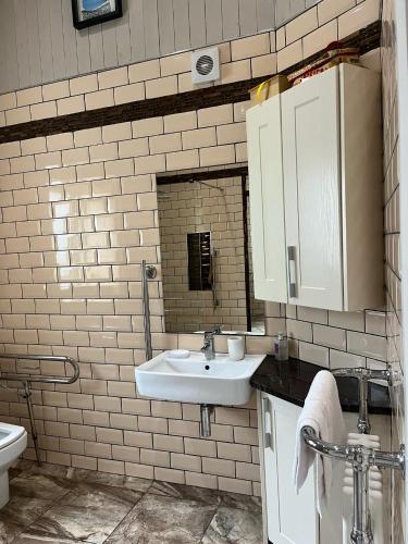 a white tiled bathroom with a sink and a toilet at Stone Lodge Bed & Breakfast in Navan