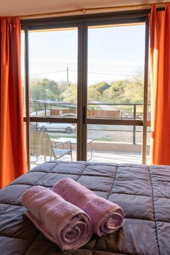 a bed with two towels on it in front of a window at Cabañas Miraluna in Villa General Belgrano